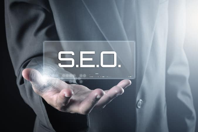 Person in a Gray Business Suit Holding Their Hand Out with the Acronym S.E.O standing for Search Engine Optimization.