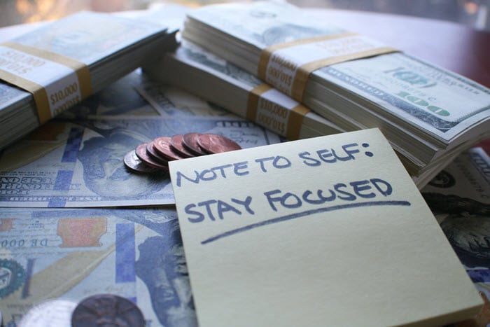 Some Stacks of US Cash and Coin along with a Note to Self: Stay Focused.